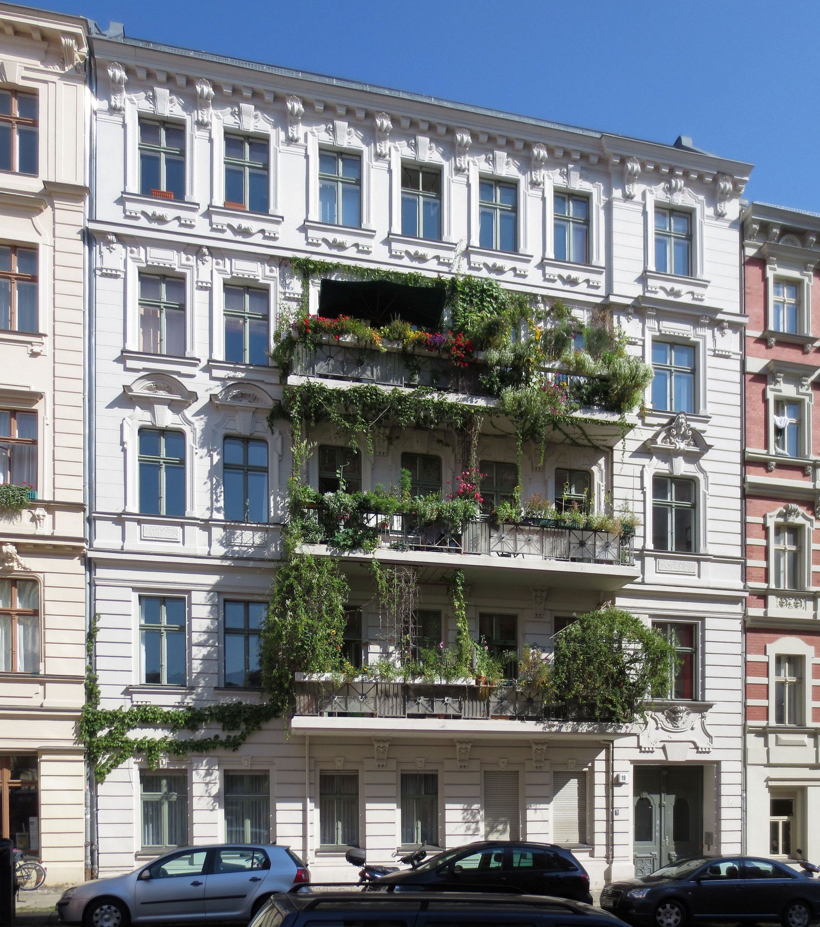 Helle Berliner Altbaufassade mit begrünten Balkonen
